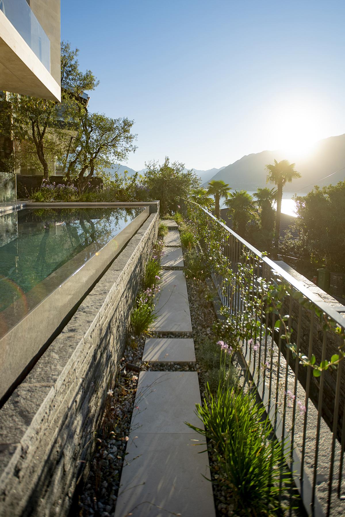 Infinity-Pool mit mediterraner Bepflanzung und Blick in die Landschaft.